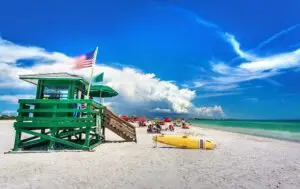 american flag flying at white sand beach and life guard stand with rescue raft
